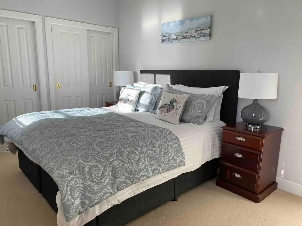 a bedroom with a large bed and a night stand at 2 bedroom Townhouse within Grade C listed Ladysbridge House 2 night minimum stay in Ladysbridge Station