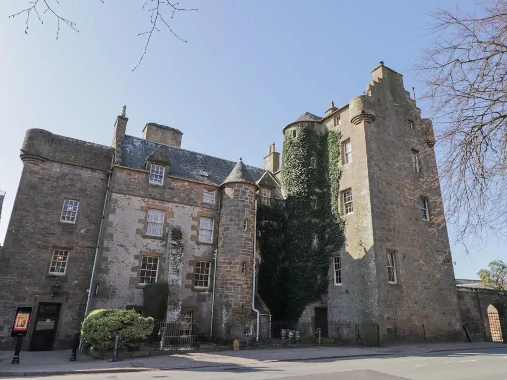 an old castle with ivy on the side of it at Aspen Spa Apartment in Dornoch