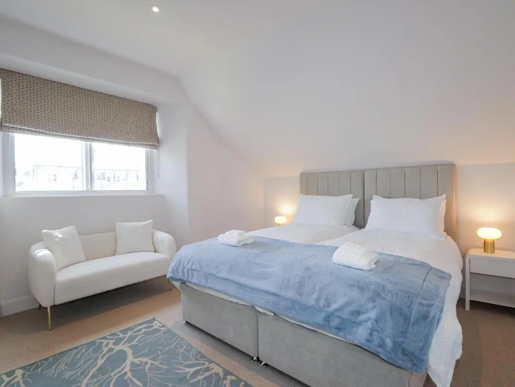 a bedroom with a large bed and a chair at Aspen Spa Apartment in Dornoch