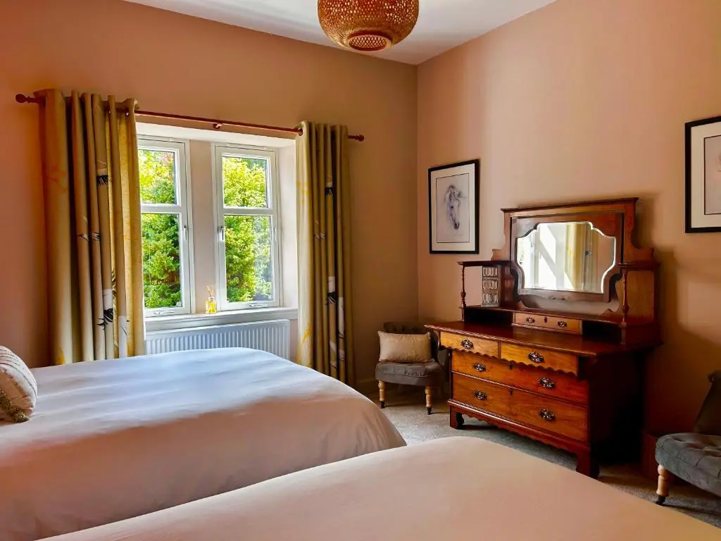 a bedroom with two beds and a mirror and a dresser at Clashmore House Garden Cottage Dornoch in Dornoch