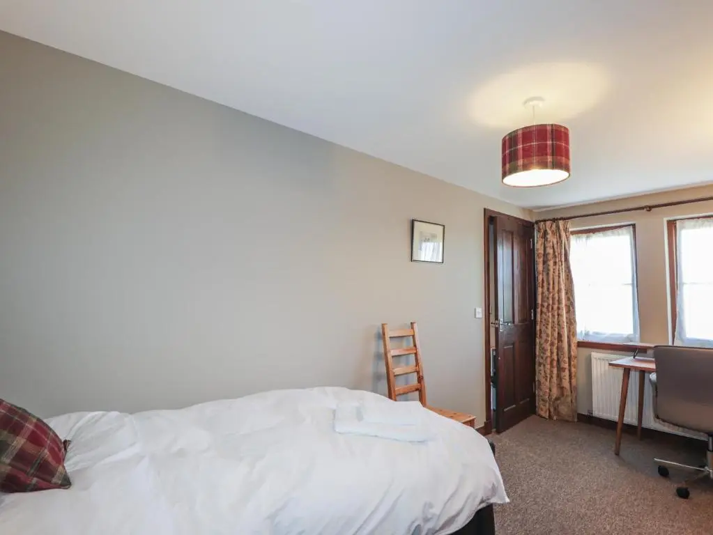 a bedroom with a bed and a desk and a chair at Fishers Cottage in Inverness