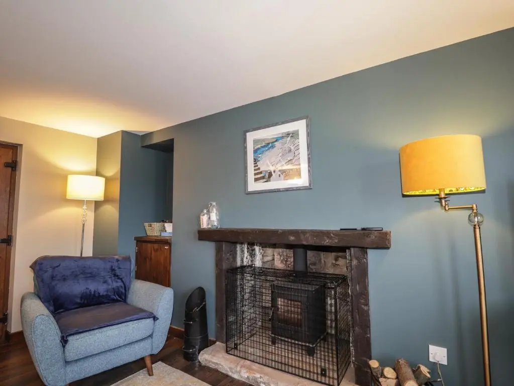 a living room with a chair and a fireplace at Fishers Cottage in Inverness