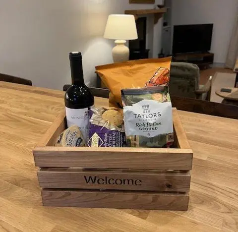 a wooden box with a bottle of wine and cheese at Balnain Street Cottage in Inverness