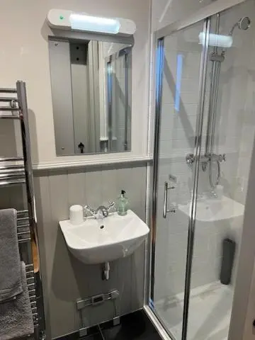 a bathroom with a sink and a shower with a mirror at Balnain Street Cottage in Inverness