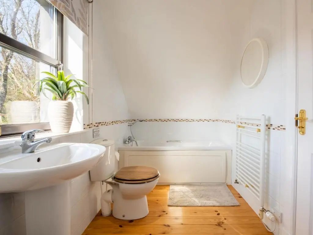 a white bathroom with a toilet and a sink at Villa Drover's Lodge by Interhome in Drumnadrochit