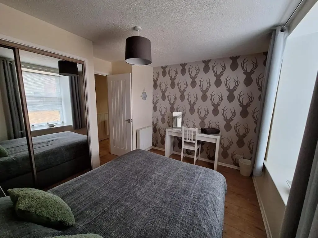 a bedroom with a bed and a desk with a table at Inverness City Centre Apartment! in Inverness