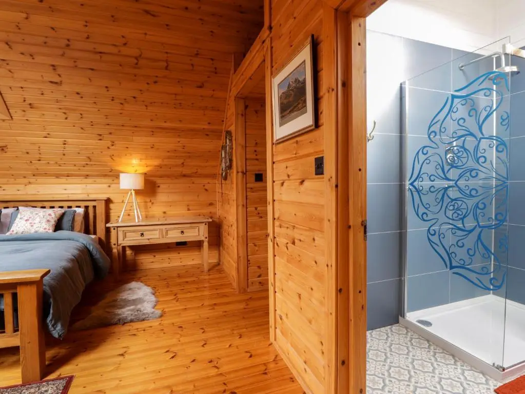 a bedroom in a log cabin with a bed and a shower at The Lodge in Beauly