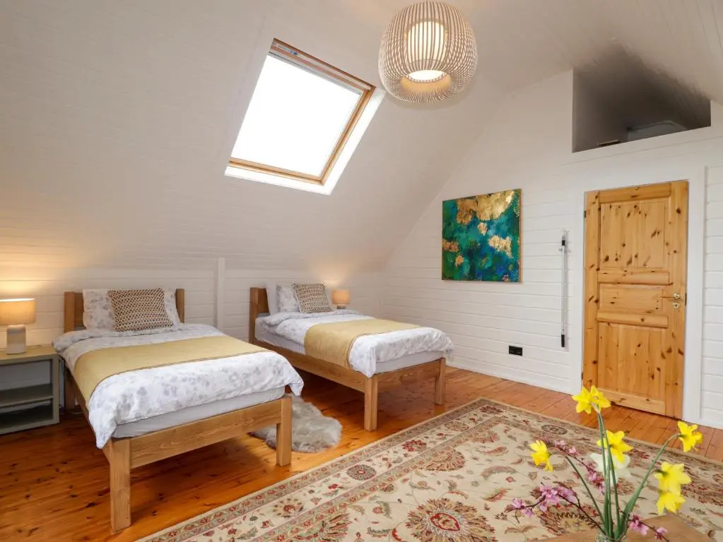 a attic bedroom with two beds and a window at The Lodge in Beauly