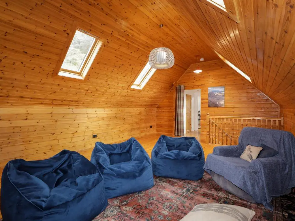 a living room with blue furniture in a wooden ceiling at The Lodge in Beauly