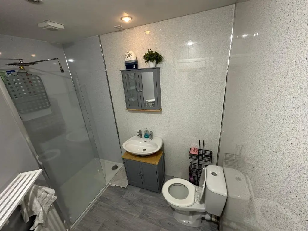 a bathroom with a toilet and a sink and a shower at Impala Apartment in Wick