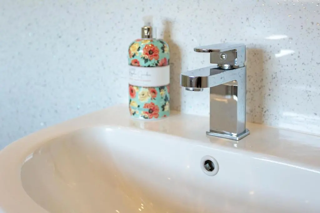 a sink with a soap dispenser and a bottle on it at Old Surgery Guest House in Ullapool