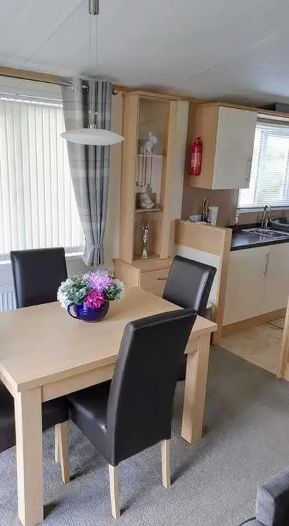 a dining room table with chairs and a kitchen at Dune Haven Luxury Beachside Lodge in Lossiemouth