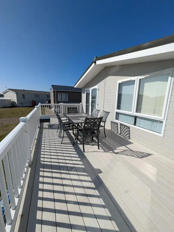 a deck with a table and chairs on a house at Dune Haven Luxury Beachside Lodge in Lossiemouth