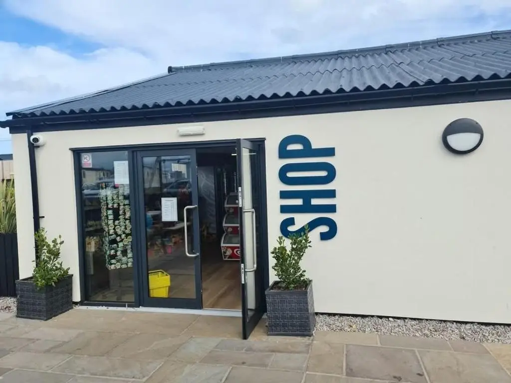 a store with a sign on the side of it at Dune Haven Luxury Beachside Lodge in Lossiemouth
