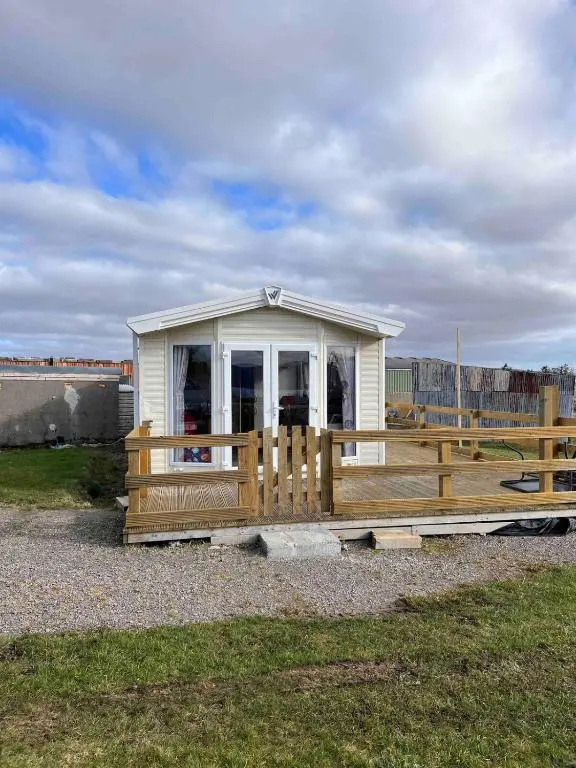 a small building with a porch and a fence at Woodend Caravan in Shinness