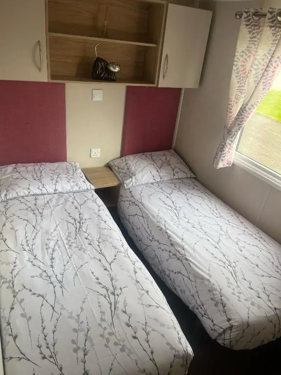 a small bedroom with a bed and a window at Woodend Caravan in Shinness