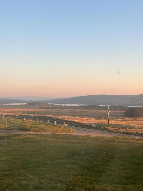 a view of a field with a road and a fence at Woodend Caravan in Shinness
