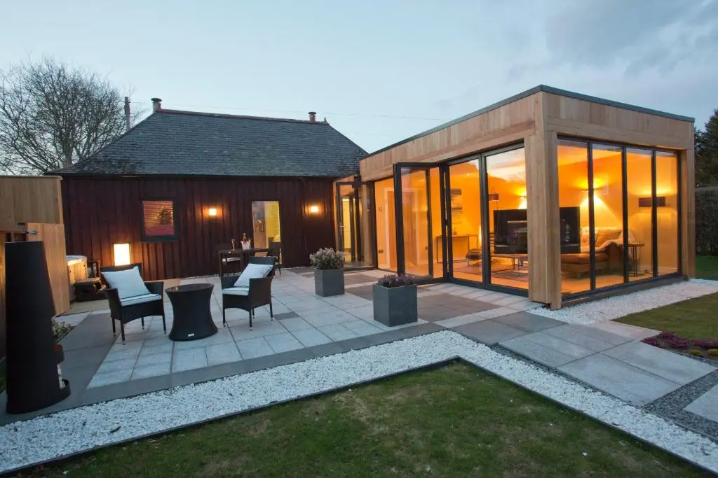 a house with glass doors and a patio at The Invergarry - Royal Deeside Luxury 5 star Couples Retreat with Hot Tub, Aboyne in Aboyne