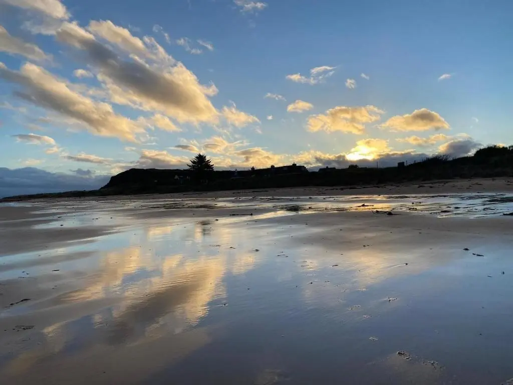 a beach with a reflection of the sky in the sand at Cosy fisherman cottage in seaside village in Shandwick
