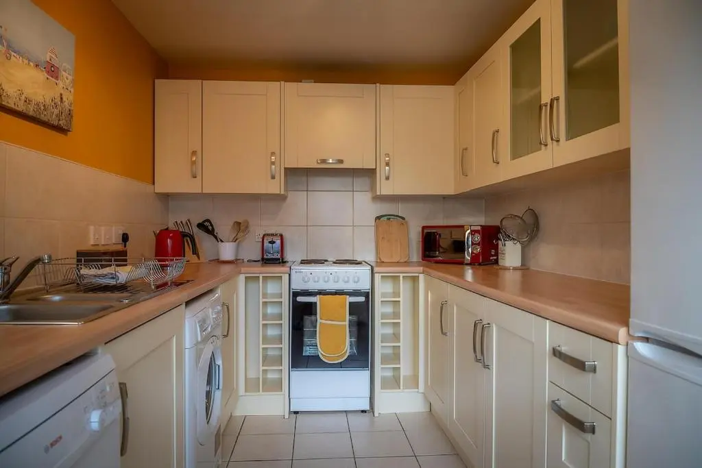 a kitchen with white cabinets and a stove top oven at Cosy fisherman cottage in seaside village in Shandwick