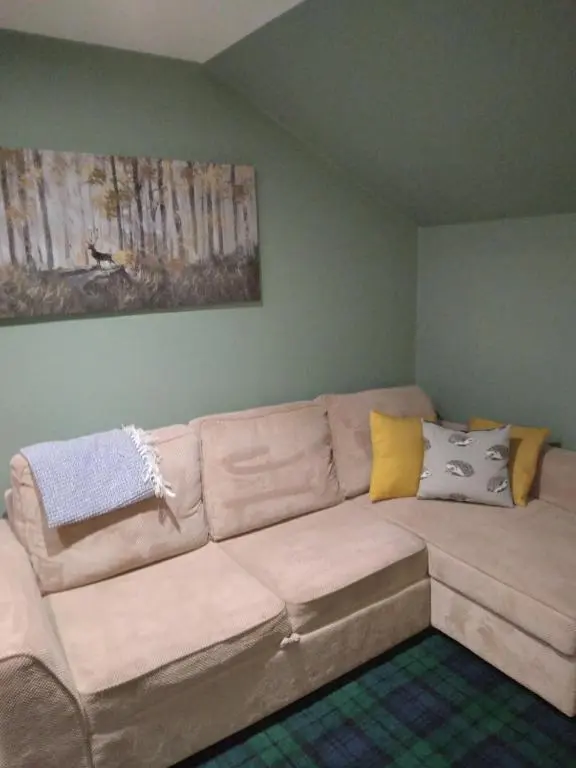 a living room with a large couch with pillows at Cosy central 1 bedroom apartment, free parking in Inverness