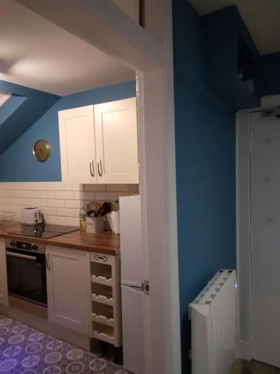 a kitchen with white cabinets and a blue wall at Cosy central 1 bedroom apartment, free parking in Inverness