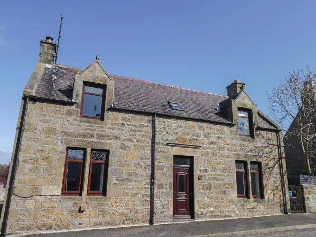 an old stone building with red doors and windows at 6 New Street in Elgin