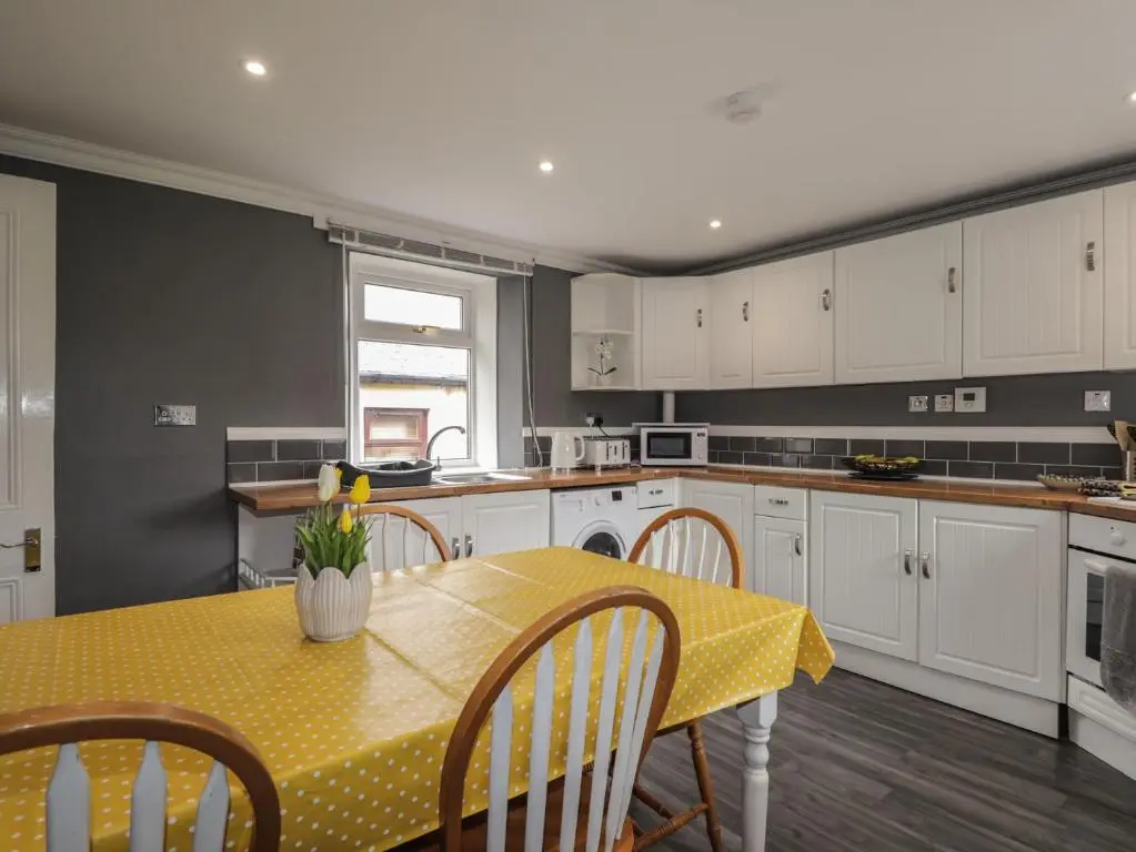 a kitchen with a table with a yellow table cloth on it at 6 New Street in Elgin