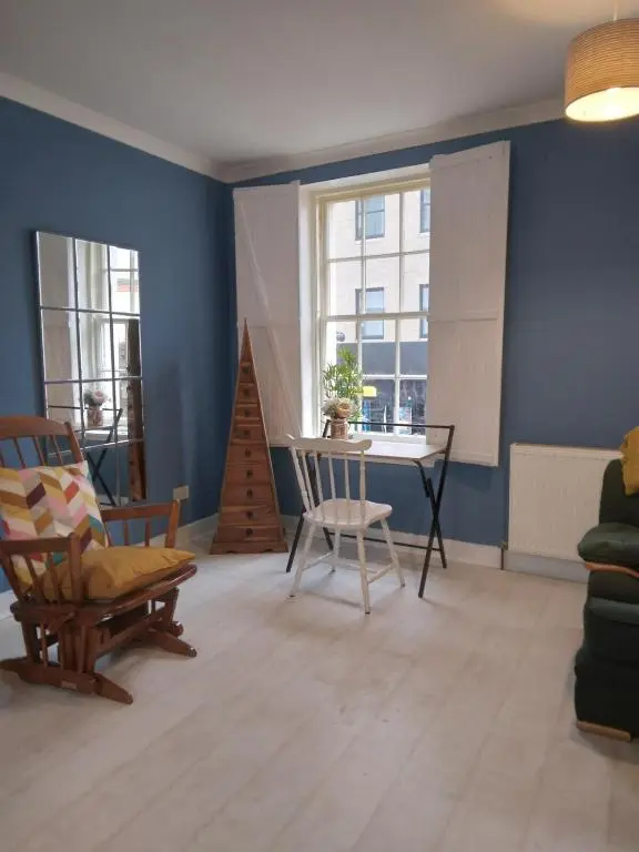 a living room with blue walls and a table and chairs at Cosy central 2 bedroom apartment - free parking in Inverness