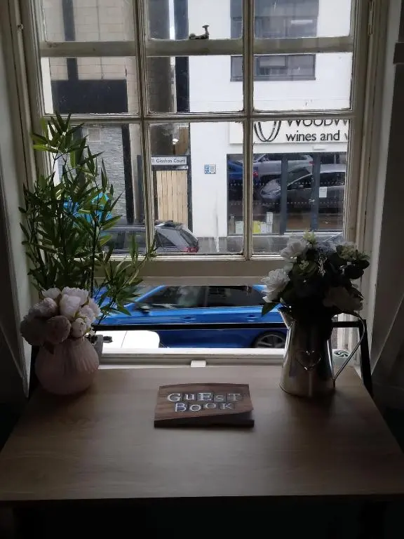 a window with flowers and a book on a table at Cosy central 2 bedroom apartment - free parking in Inverness