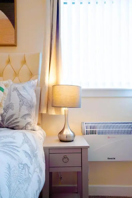 a bed with a lamp on a nightstand next to a window at Lovely & Bright 2 Bed Apartment in Inverness