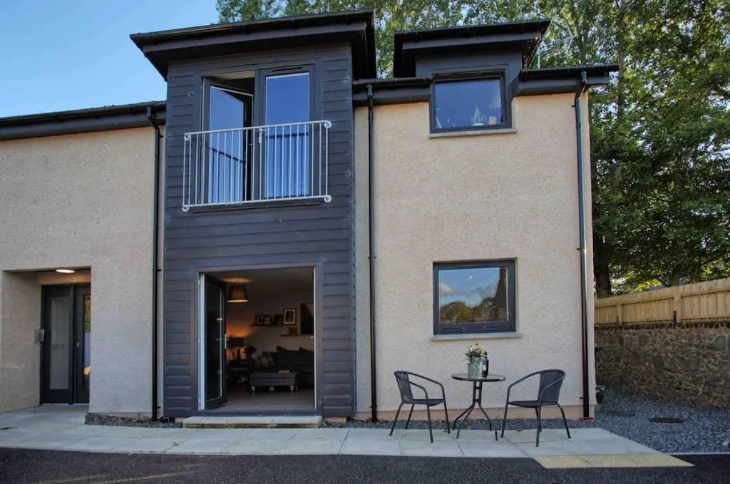 a house with chairs and a table in front of it at Luxury Apartment Alford Aberdeenshire in Alford