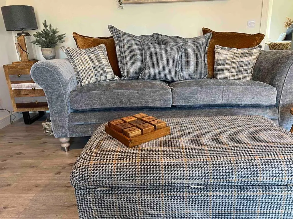 a living room with a couch and a tray on a ottoman at Luxury Apartment Alford Aberdeenshire in Alford