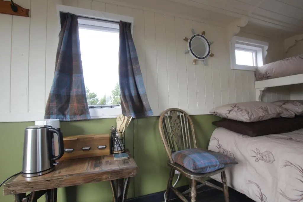 a bedroom with a bed and a table and a table sidx sidx sidx at The Cairn Hut in Lybster