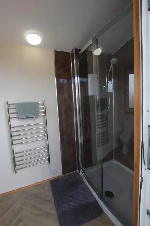 a bathroom with a shower with a glass door at The Cairn Hut in Lybster