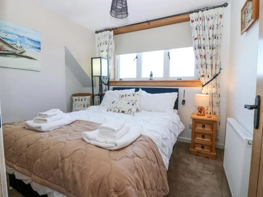 a bedroom with a bed with towels on it at Periwinkle Cottage in Banff