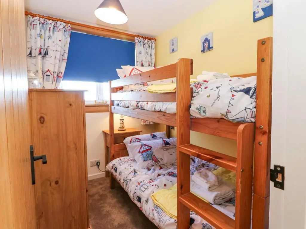 a bedroom with two bunk beds and a window at Periwinkle Cottage in Banff