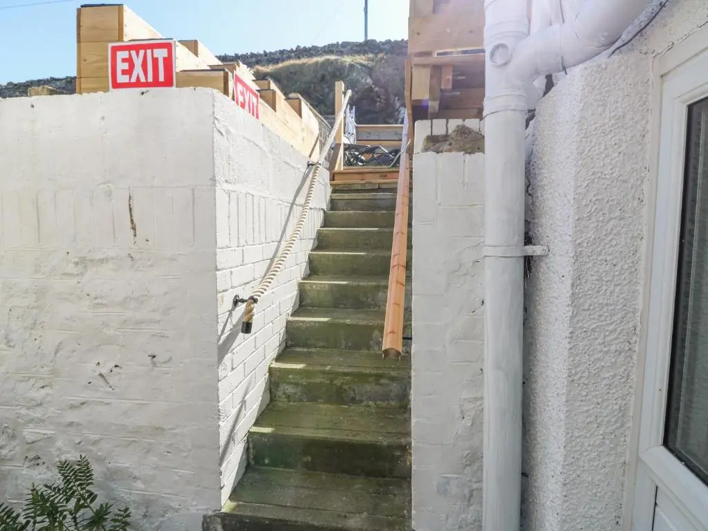 a stairway leading up to a building with aexit sign at Periwinkle Cottage in Banff