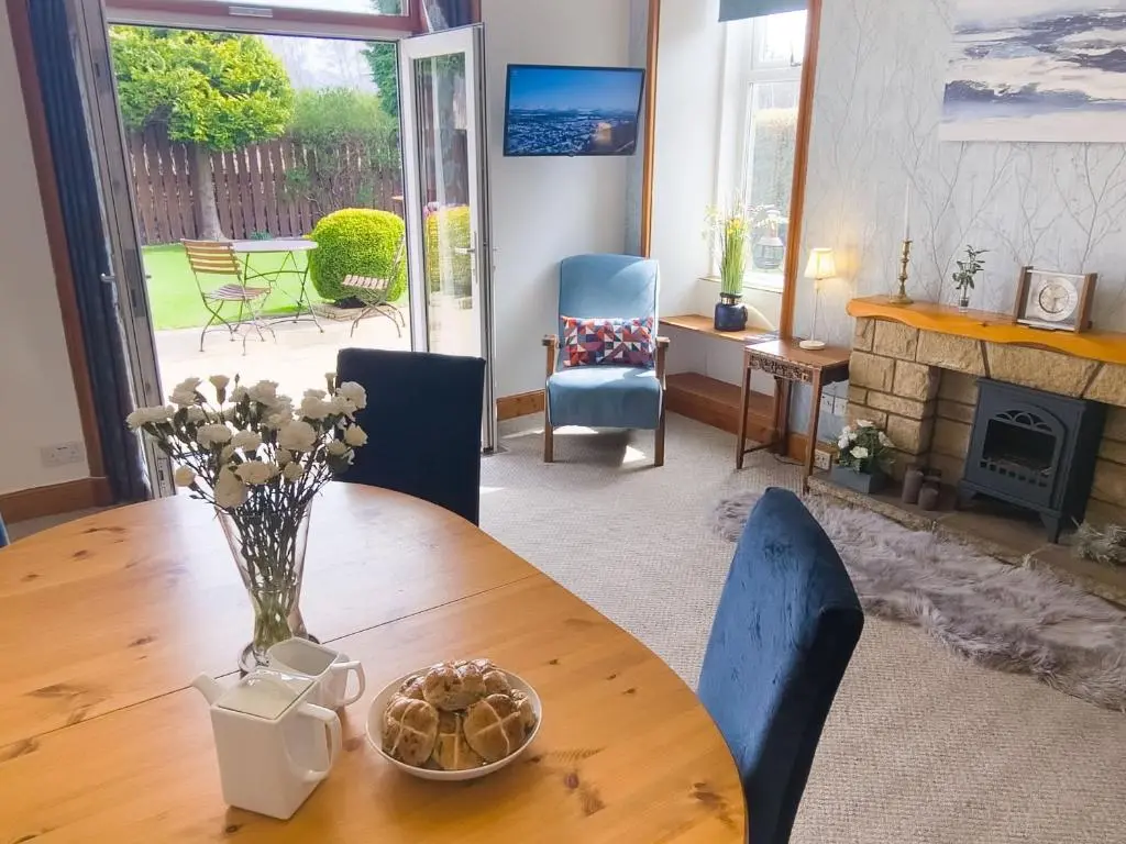 a dining room table with a vase of flowers on it at Birchview in Aviemore
