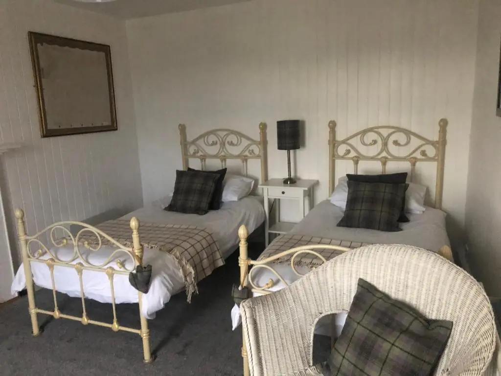 a bedroom with two beds and a chair in it at The Hoose in Helmsdale