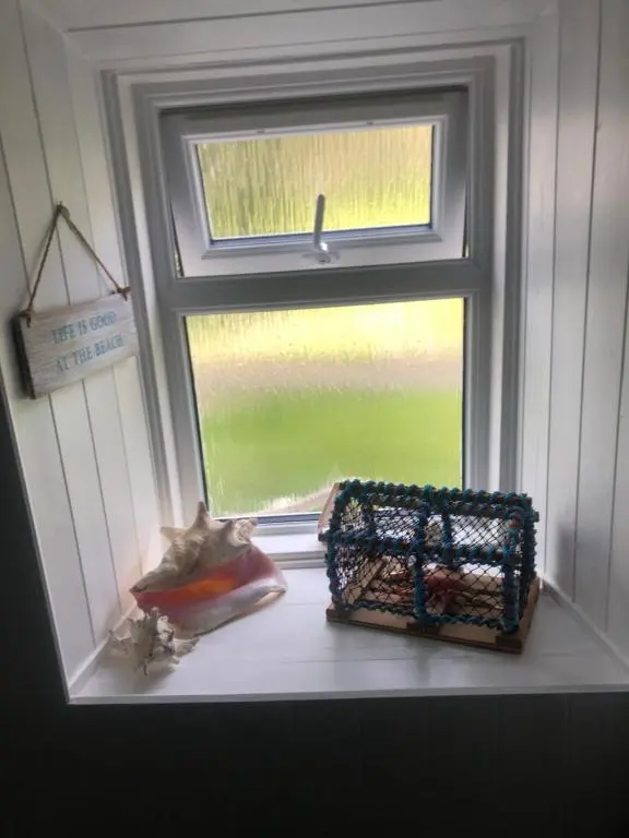 a window with a cat sitting on a window sill at The Hoose in Helmsdale