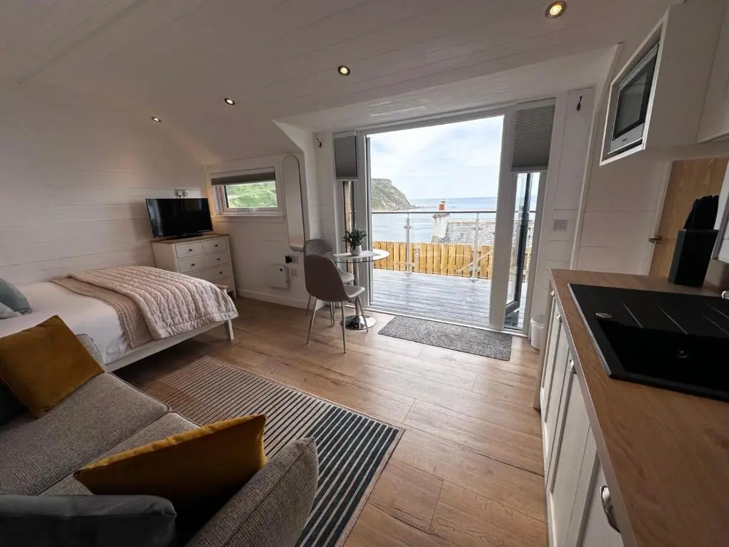 a bedroom with a bed and a kitchen with a balcony at Gamrie Beach Bothy in Gardenstown