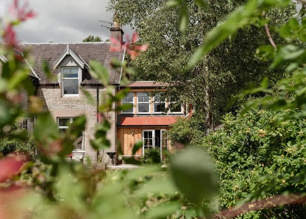 a house is seen through the trees at Broomfeild Bothy Comes with a Sauna in Boat of Garten