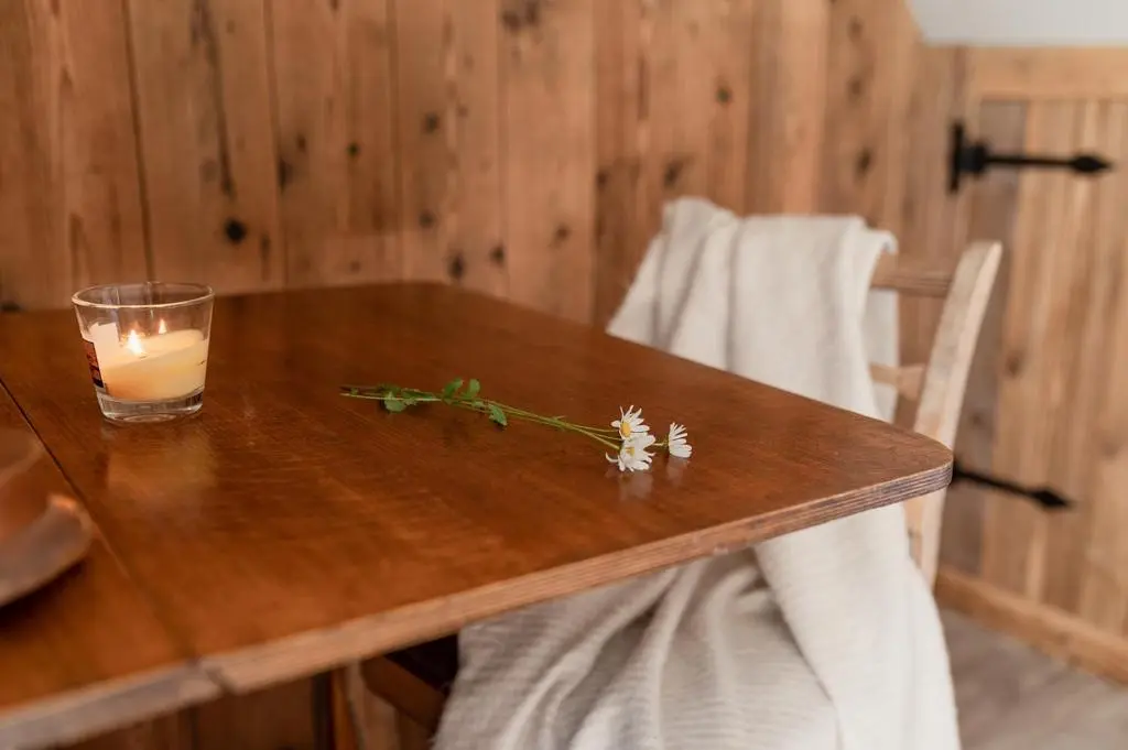 a candle and flowers on a wooden table at Broomfeild Bothy Comes with a Sauna in Boat of Garten