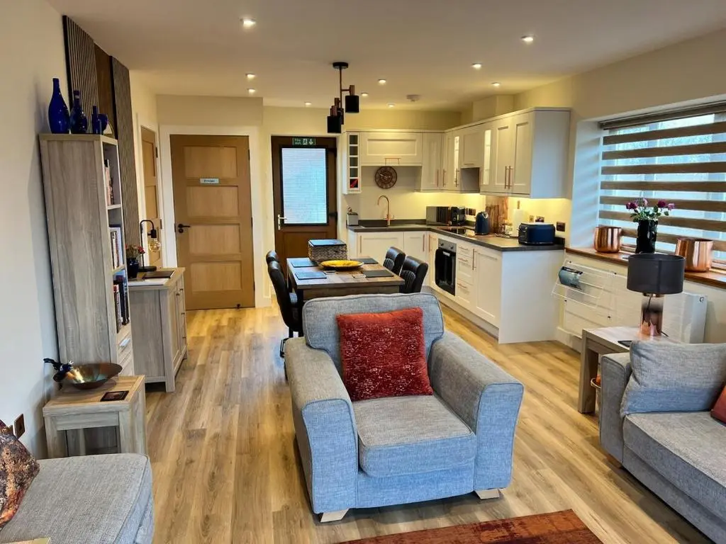 a living room with two couches and a kitchen at Dalchalm Hideaway in Brora