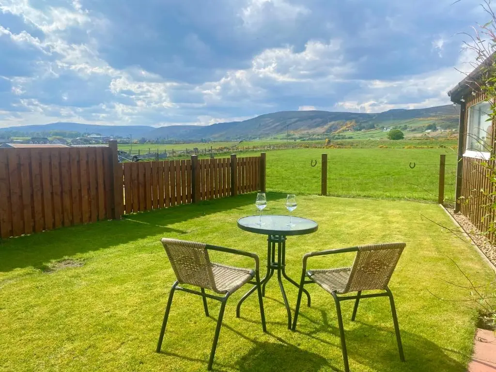 a table with two chairs and a table with wine glasses at Dalchalm Hideaway in Brora