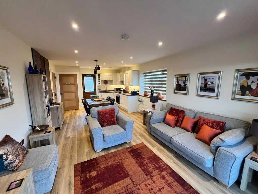 a living room with two couches and a kitchen at Dalchalm Hideaway in Brora