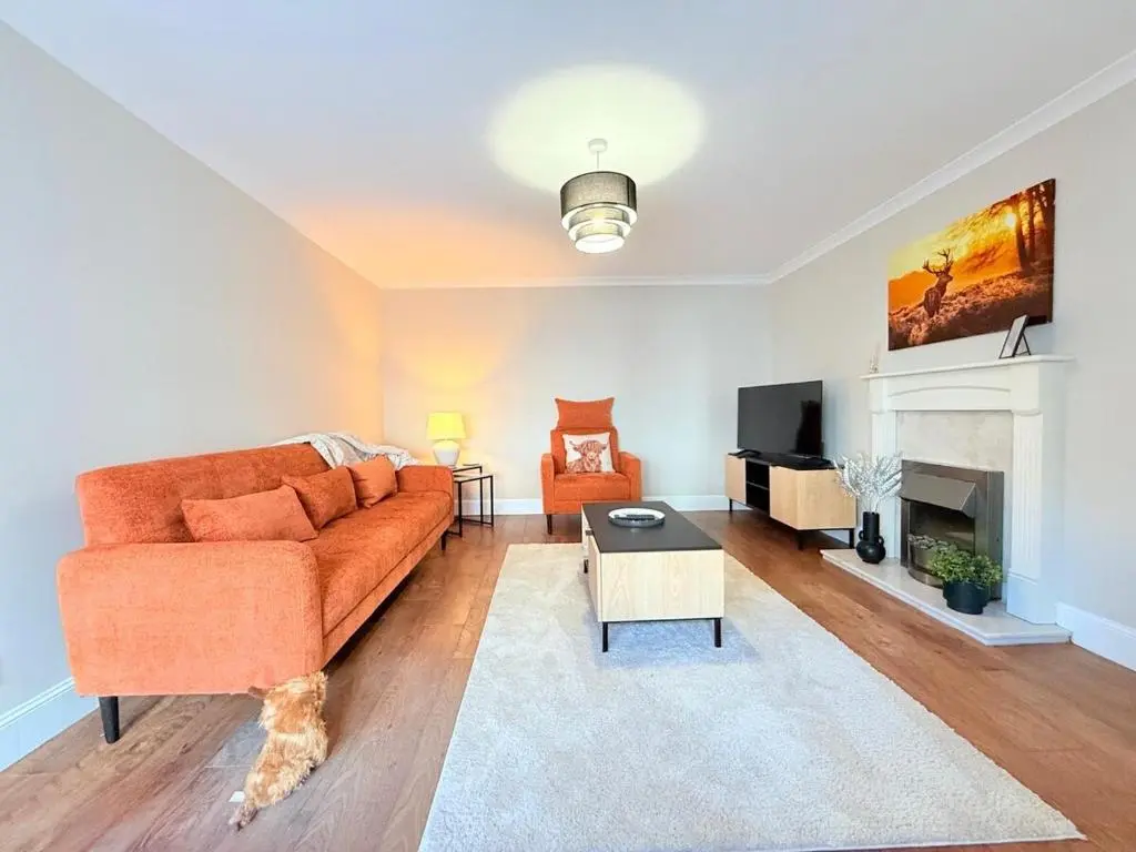 a living room with a orange couch and a fireplace at Sea Breeze Cottage short walk to the beach, Nairn in Nairn