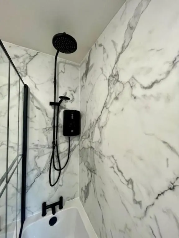 a bathroom with a shower and a white marble wall at Sea Breeze Cottage short walk to the beach, Nairn in Nairn