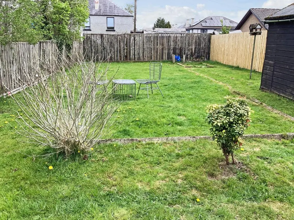 a backyard with a table and a bush in the grass at Seasgair in Dingwall
